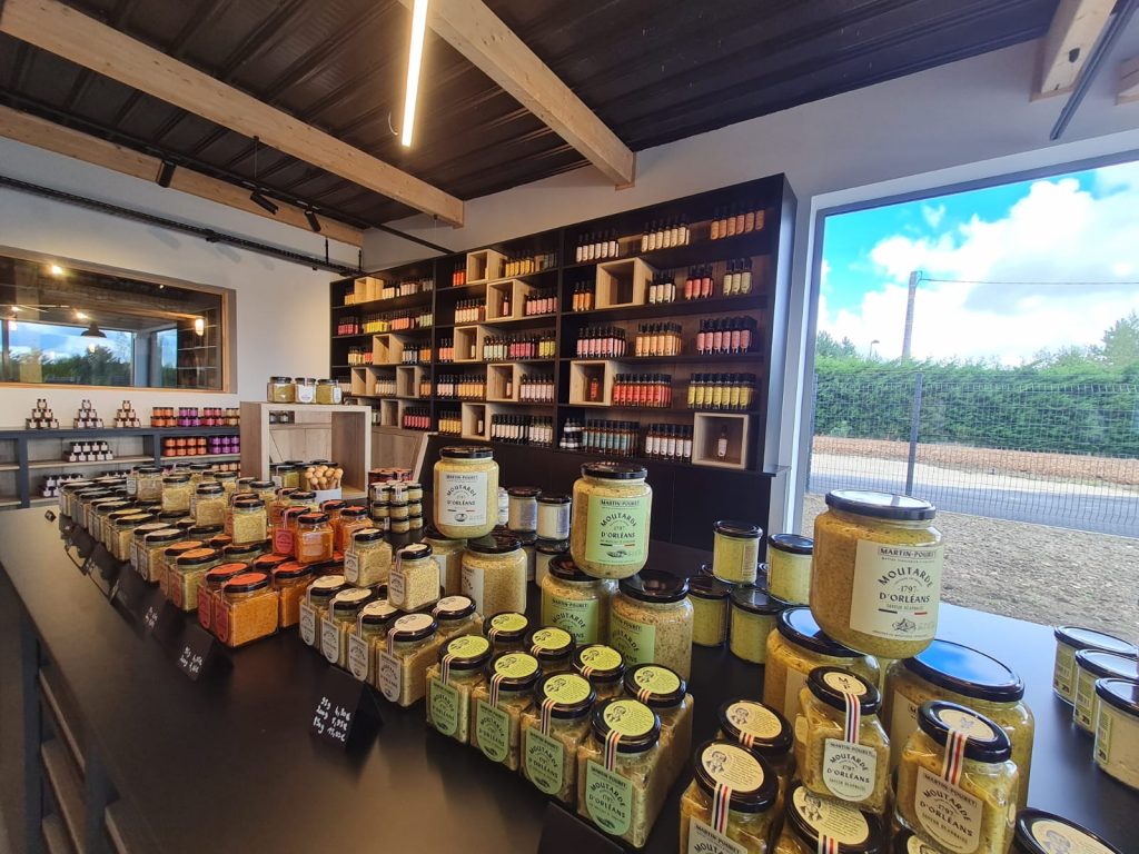 Étalage des produits Martin Pouret dans la boutique des nouveaux ateliers, incluant moutardes, vinaigres et autres condiments.