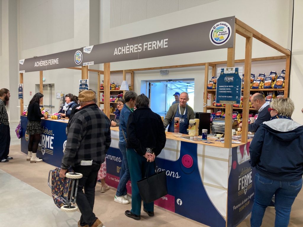 Le stand de 18m² d'Achères ferme avec des étagères garnies de pommes de terre en filet.