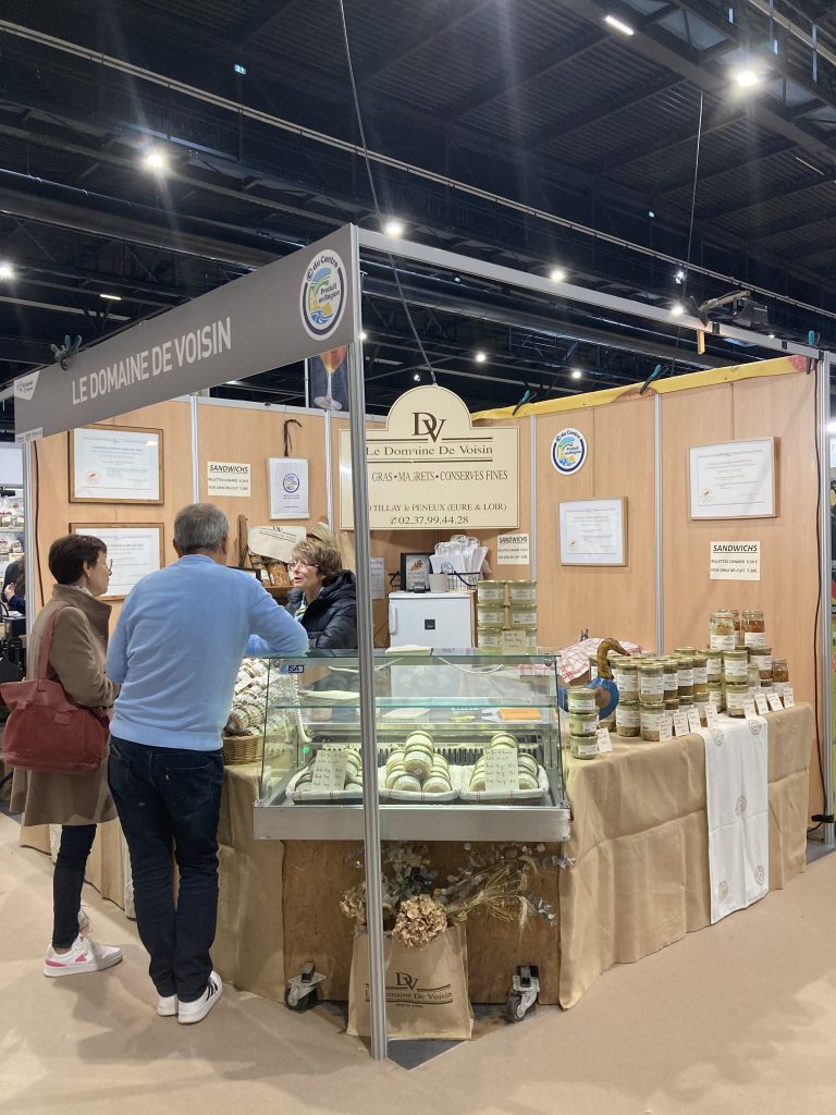 Le stand de Domaine de Voisin avec une vitrine dans l'angle du stand et des bocaux placés sur des tables de part et d'autre.