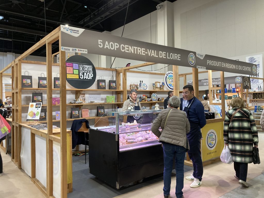 Le stand des 5 AOP Centre-Val de Loire avec une vitrine au premier plan remplie de fromages de chèvre.