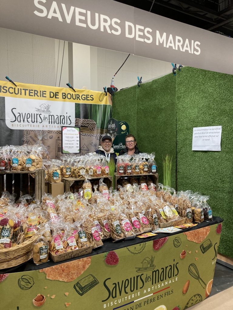 Le stand de 9m² de Saveurs des Marais. Devant une table garnie de sachets de biscuits et au fond une banderole "Saveurs des marais".