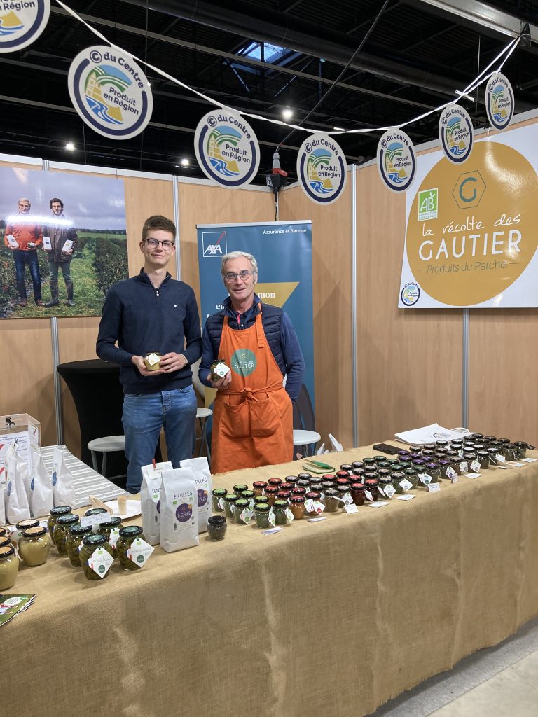 Le stand de la Récolte des Gautier avec Christophe Gautier à droite et son fils à gauche. Devant eux, une table présentant leurs produits : farine, cornichons, moutardes...